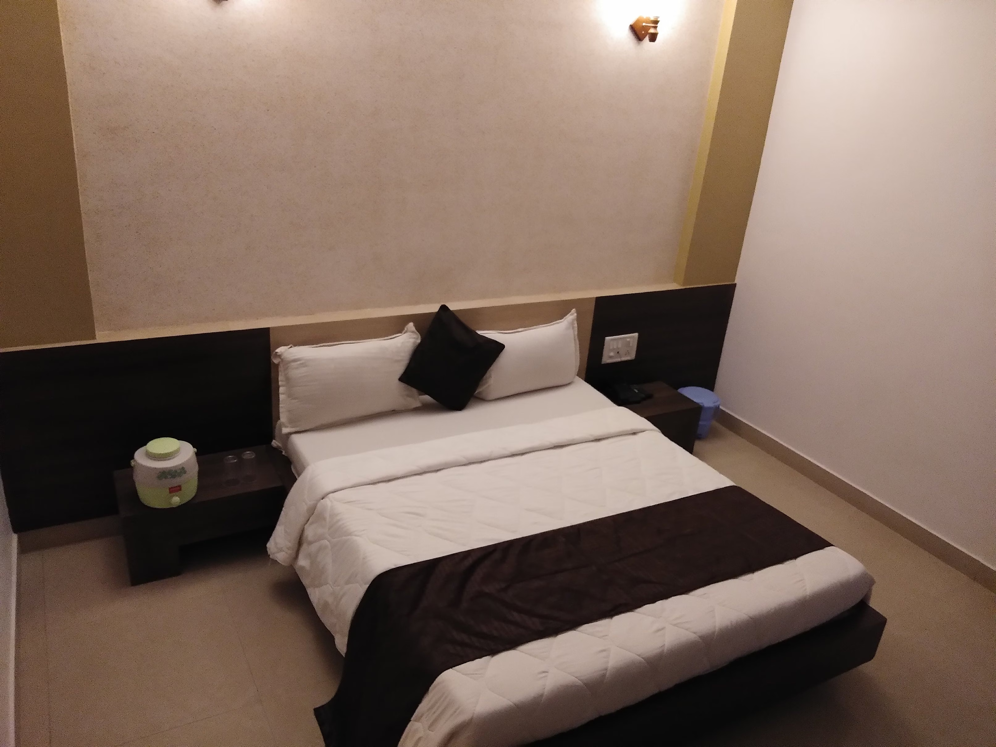 Close-up of the plush double bed in Hotel Somnath Atithigruh's air-conditioned room, showing crisp white linens.